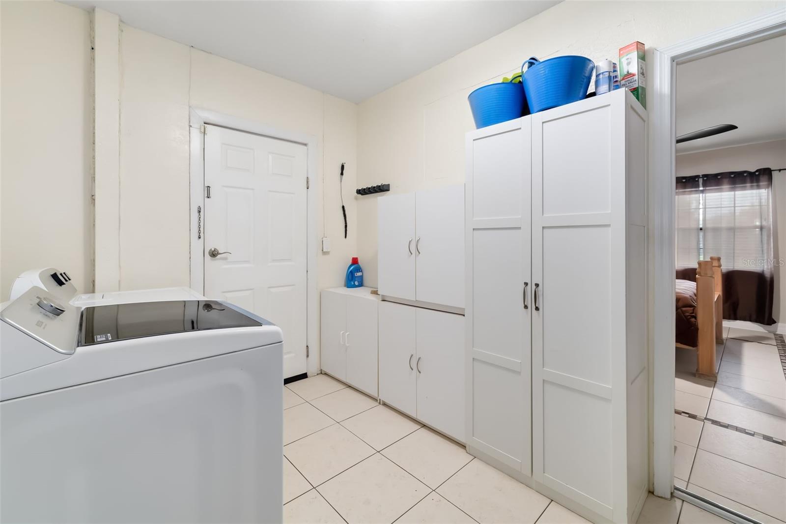 Laundry room with a top-loading washer and tall white storage cabinets.