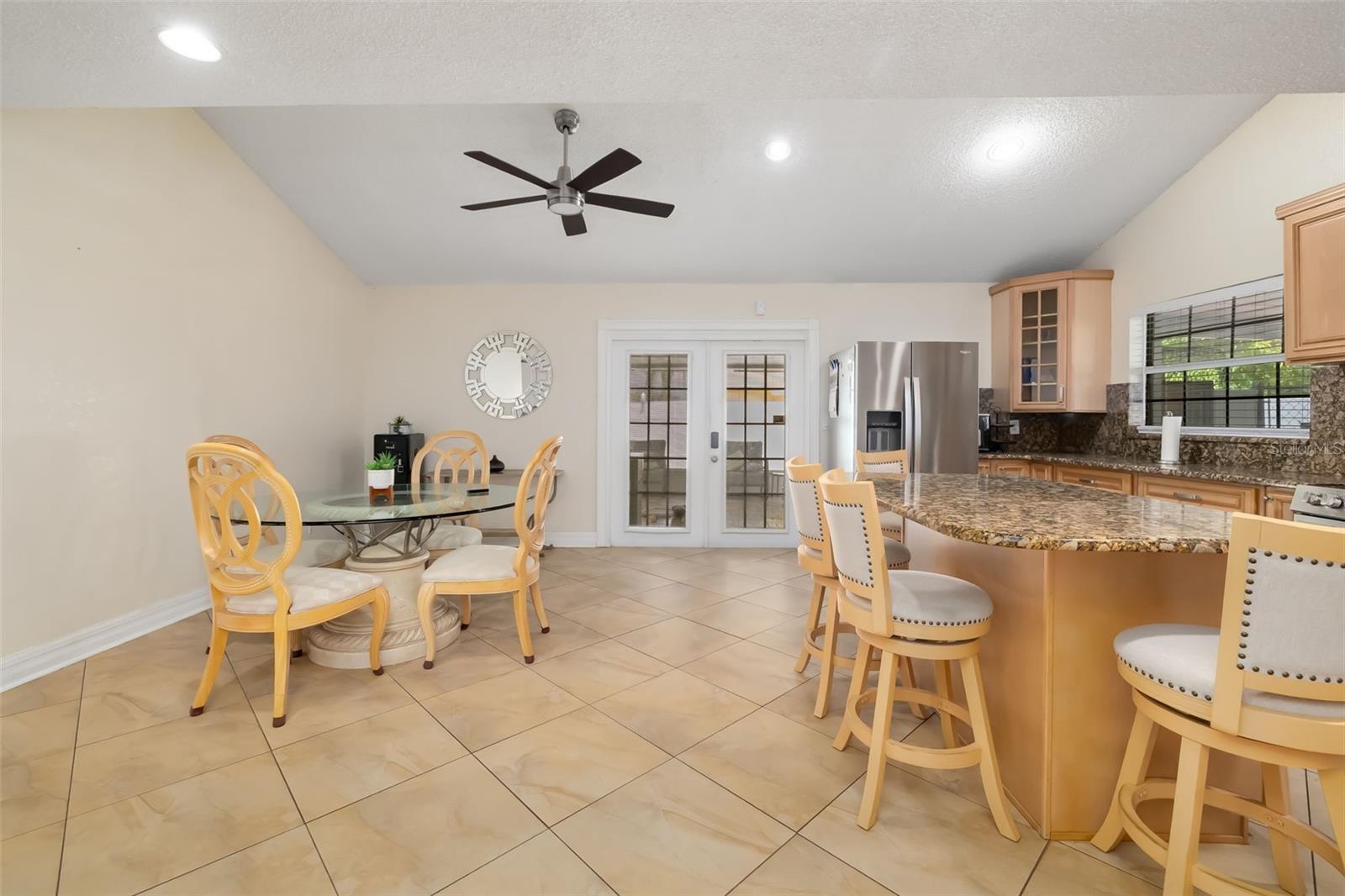 Kitchen and dining area with a granite island, light wood cabinets, and French doors.