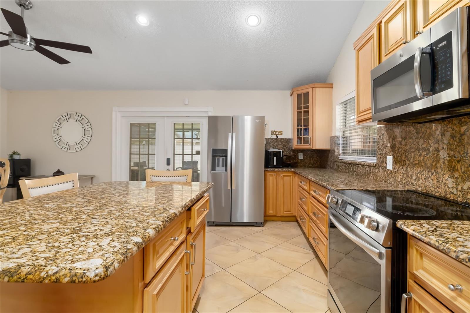 Kitchen with granite island, honey-colored cabinets, and stainless-steel appliances.