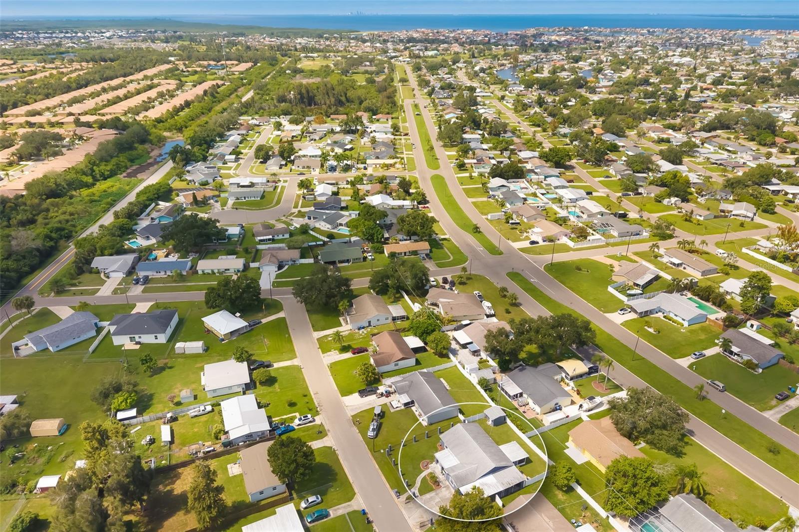 Aerial neighborhood view with a home circled among residential streets and the distant coast.