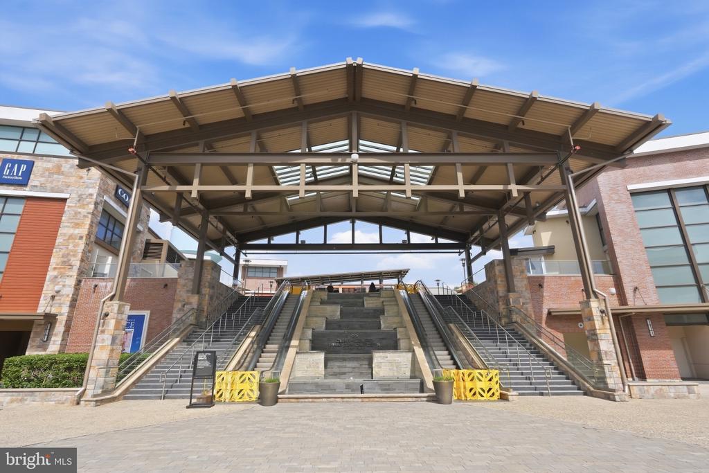 Shopping center entrance with a broad canopy over central steps and flanking stairways.