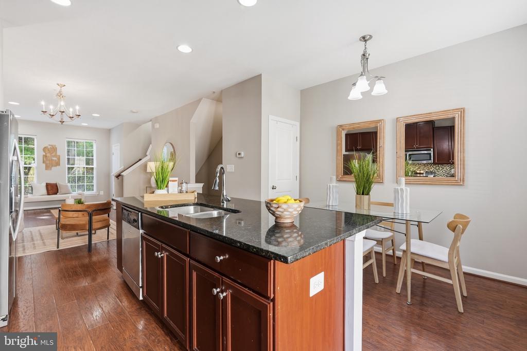 Open-plan kitchen with a granite island, dark wood cabinets, and a dining area