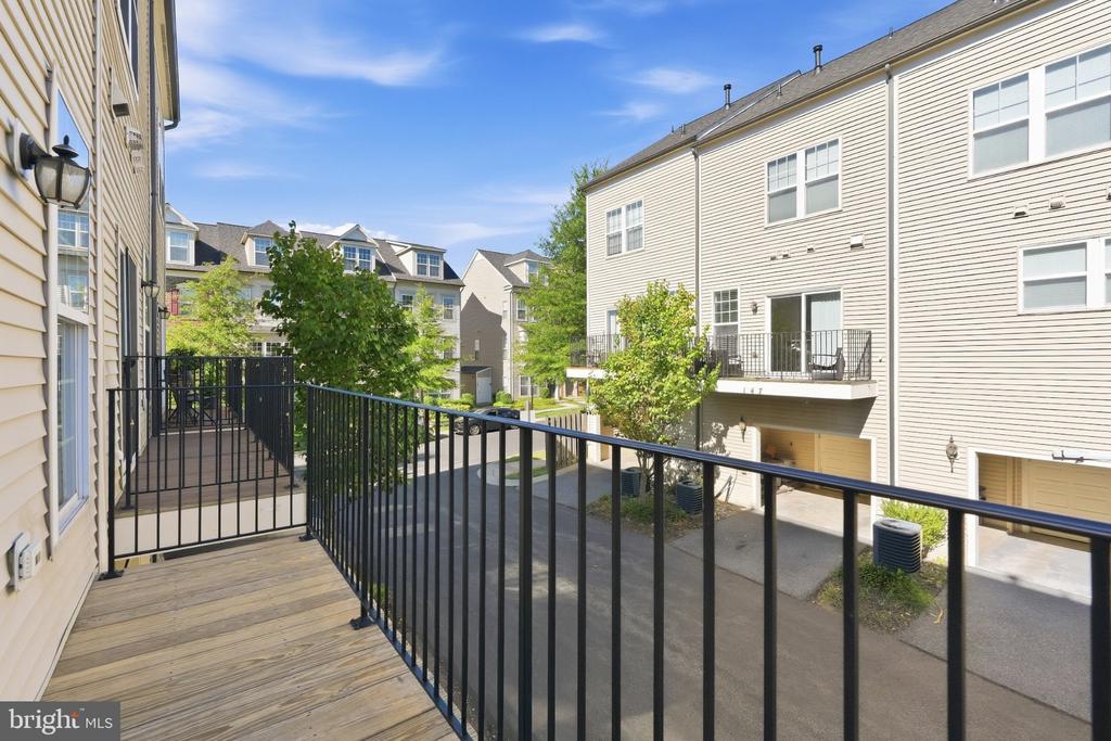 Townhouse balcony with a wooden deck and black railings overlooking neighboring homes.