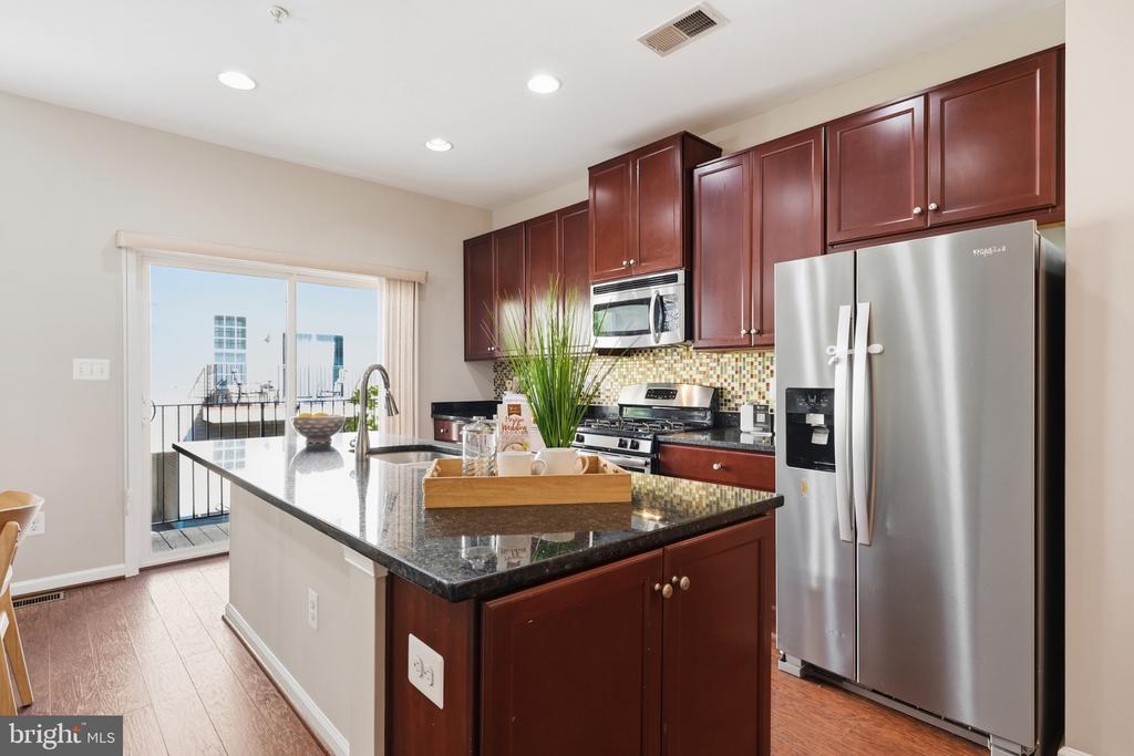 Kitchen with cherry cabinets, stainless steel appliances, granite island, and sliding doors to a balcony.