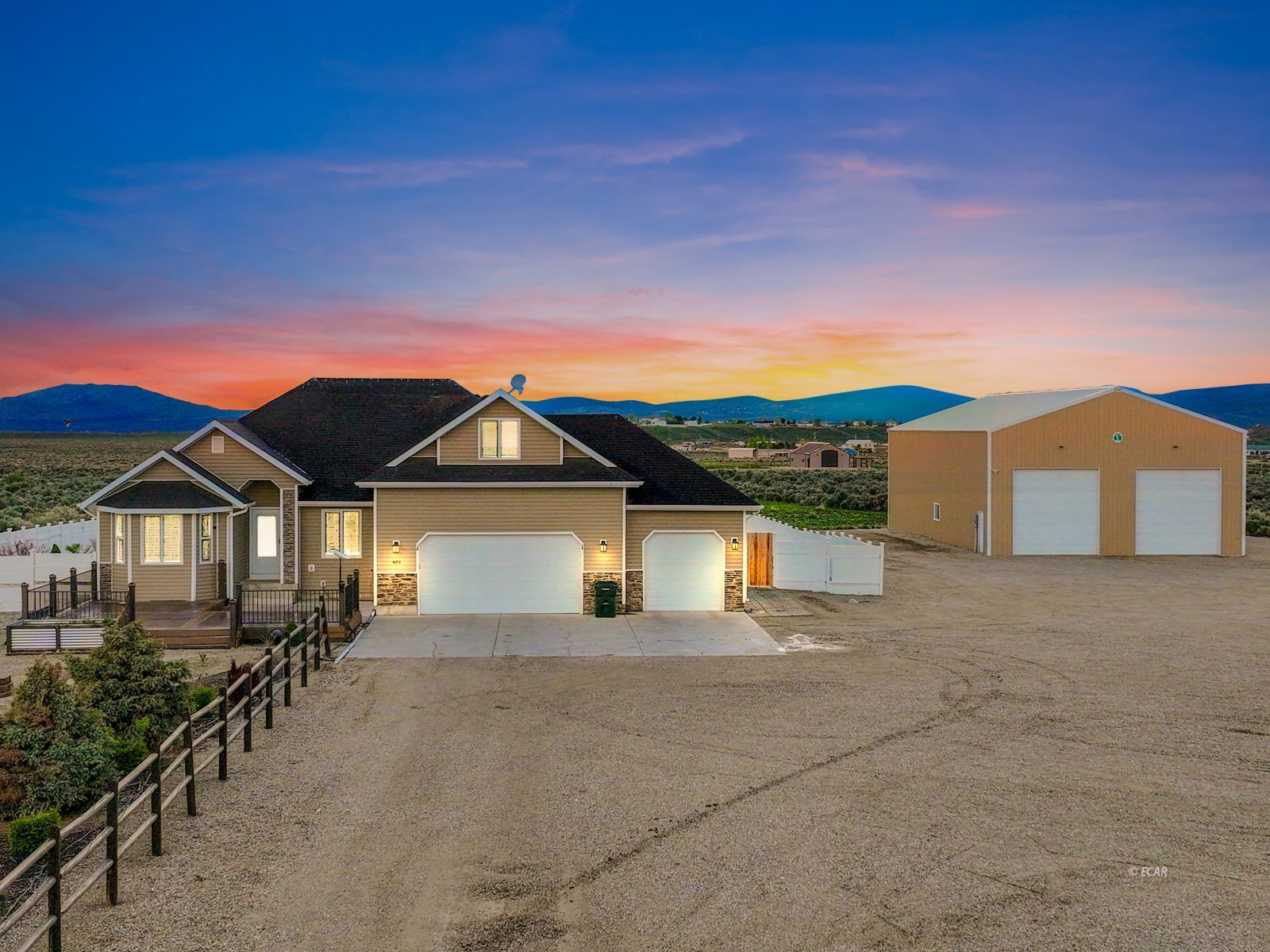 Home at 601 Diamondback Drive with a detached outbuilding and distant mountains at sunset.