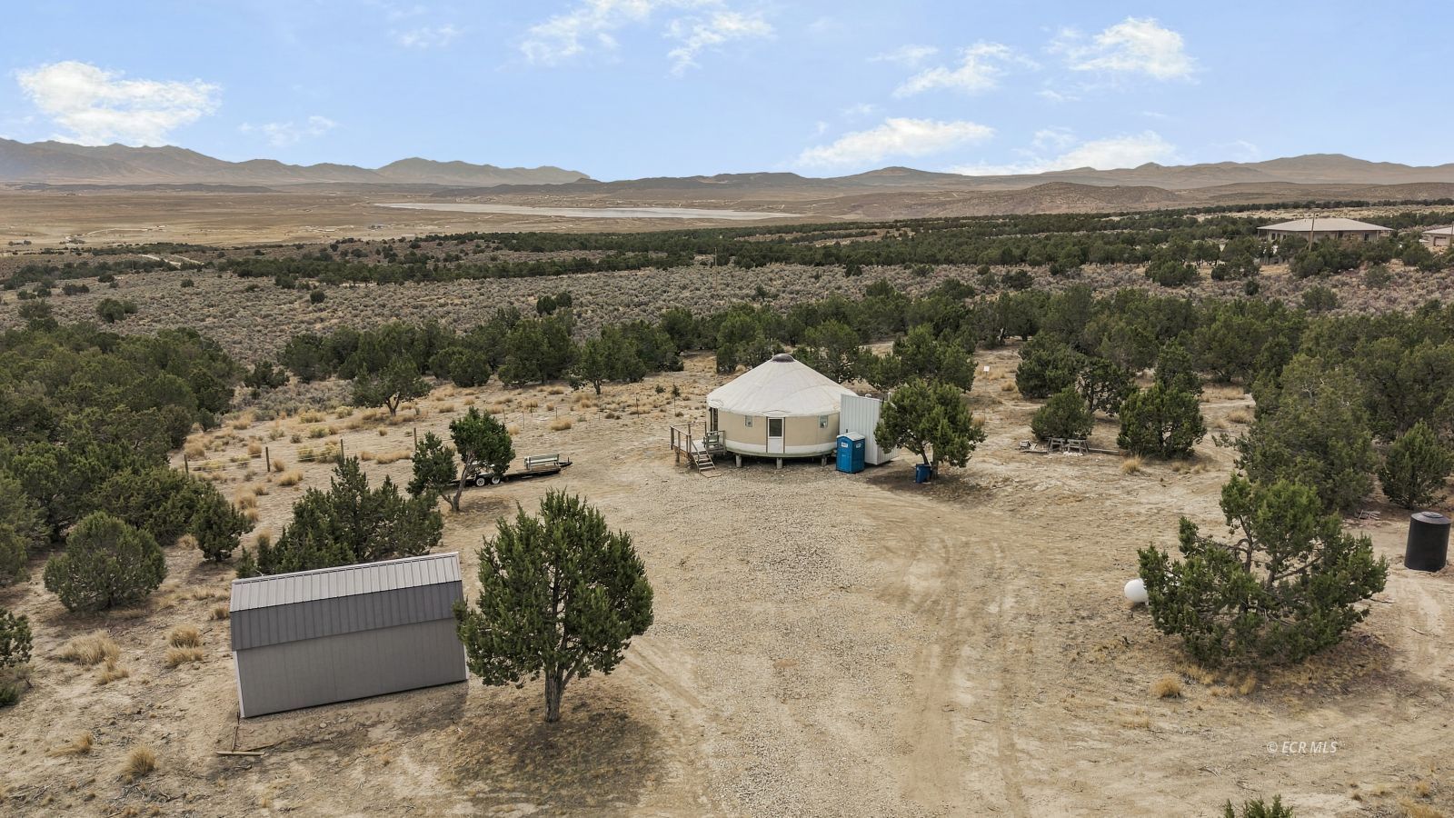 Aerial view of a round-roofed dwelling and outbuilding amid Nevada high-desert scrub.