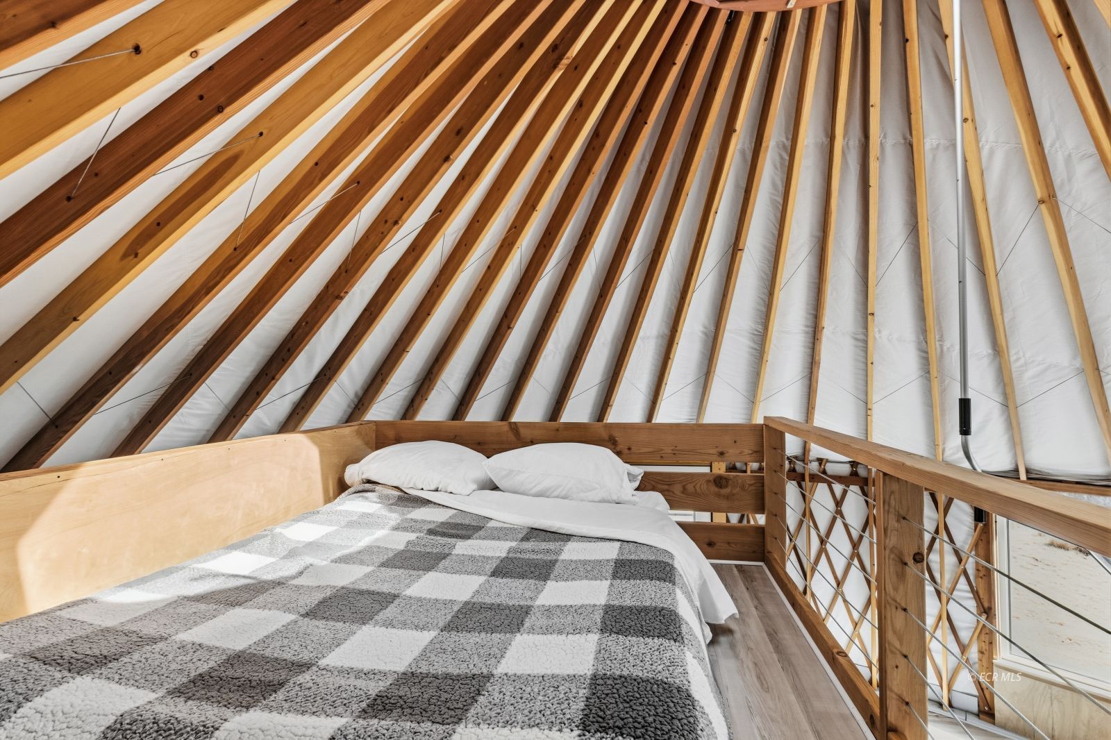 Loft bedroom with a bed beneath exposed timber rafters and a sloped ceiling.
