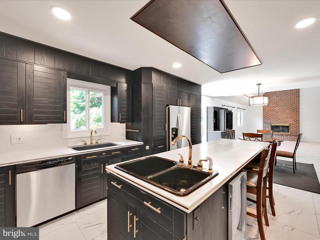 Kitchen with dark paneled cabinetry, a large white island, and stainless steel appliances.