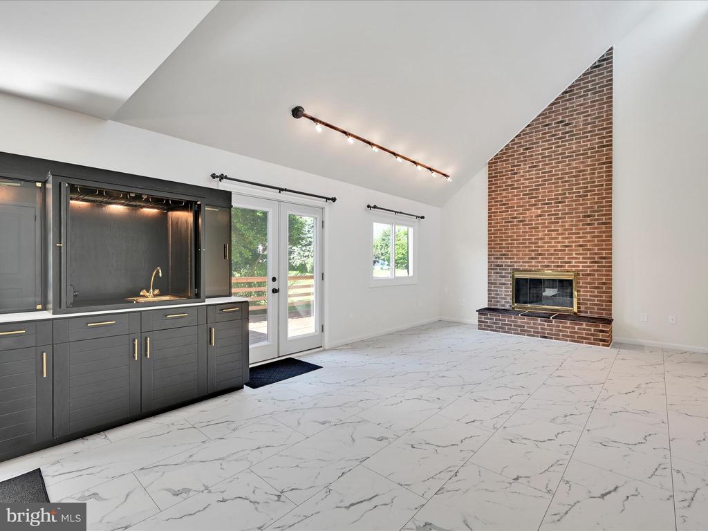 Vacant living room with a dark built-in wet bar and tall brick fireplace.