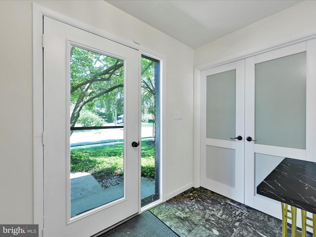 Entryway with a full-height glass door, frosted-panel sliding doors, and patterned tile floor.