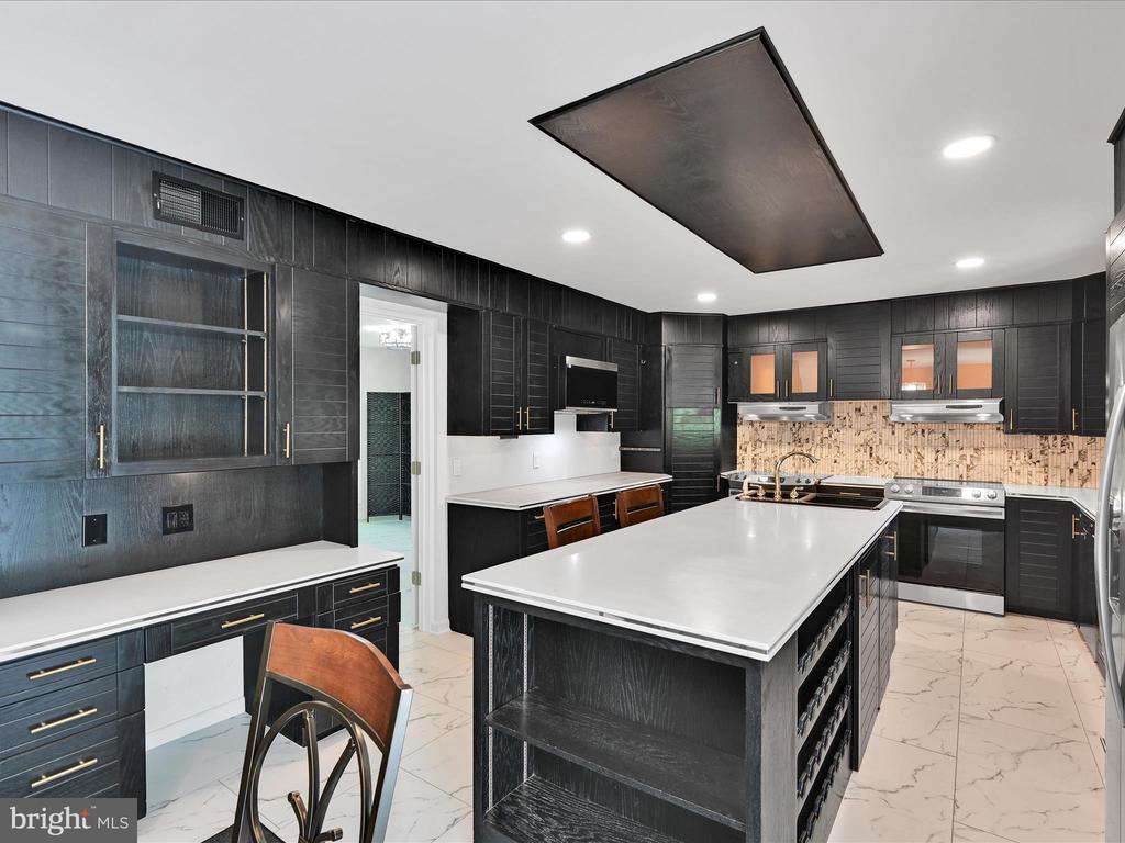 Kitchen with dark cabinetry, a large white island, stainless steel appliances, and a patterned backsplash.