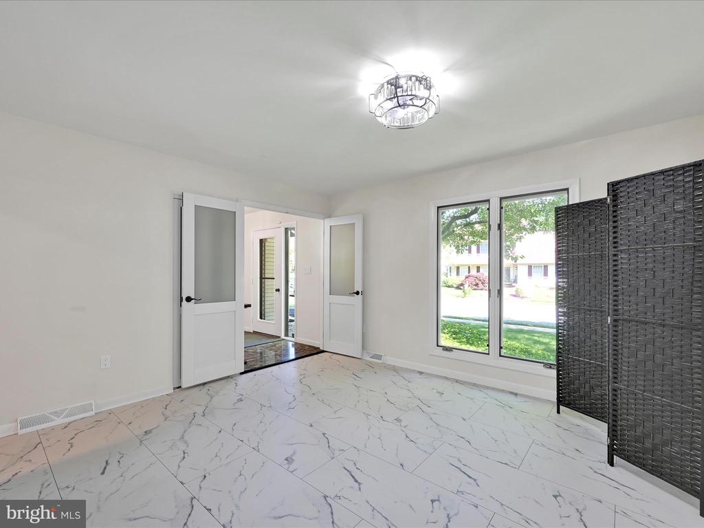 Empty room with marble-look tile flooring, wide windows, and open glass-panel doors.