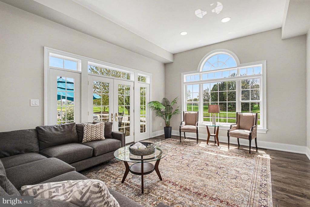 Bright living room with an arched picture window, French doors, and neutral furnishings.