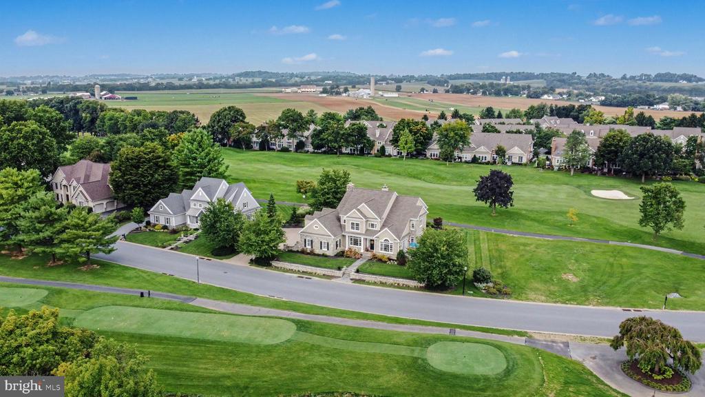 Aerial view of a large home beside a golf course, with fairways and farmland stretching into the distance.