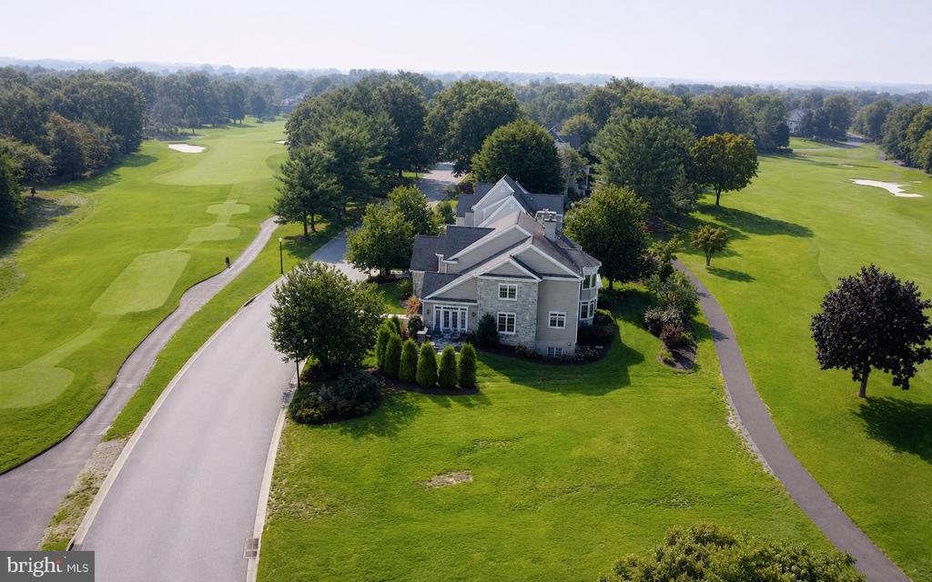 Stone house beside a golf course, with fairways and paths surrounding the property.