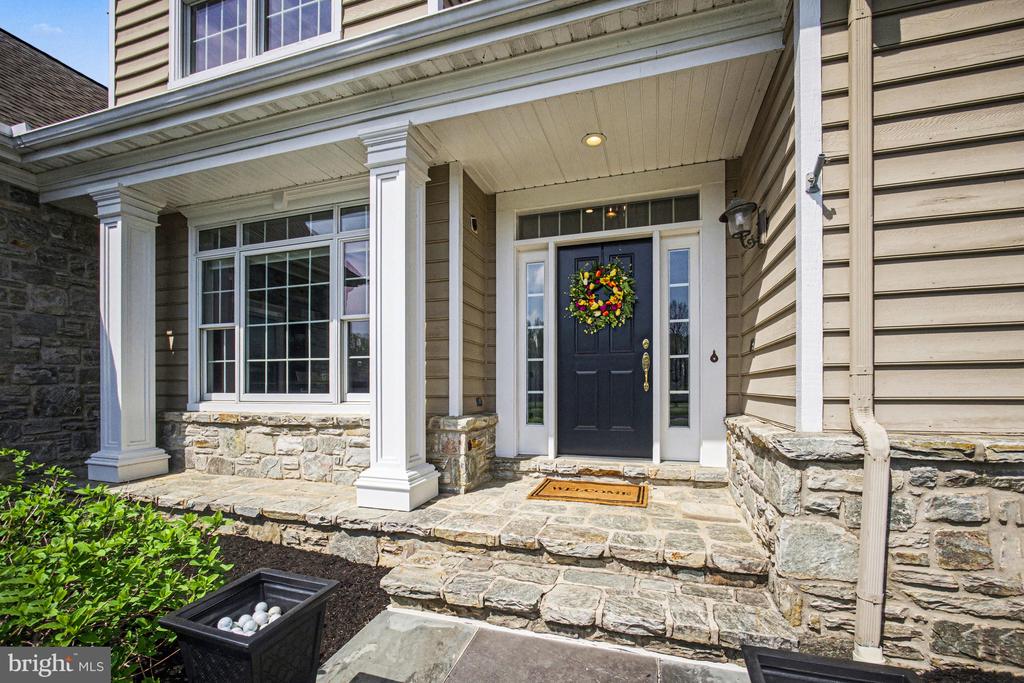 Home entrance with a dark blue door, colorful wreath, white columns, and stone porch steps.