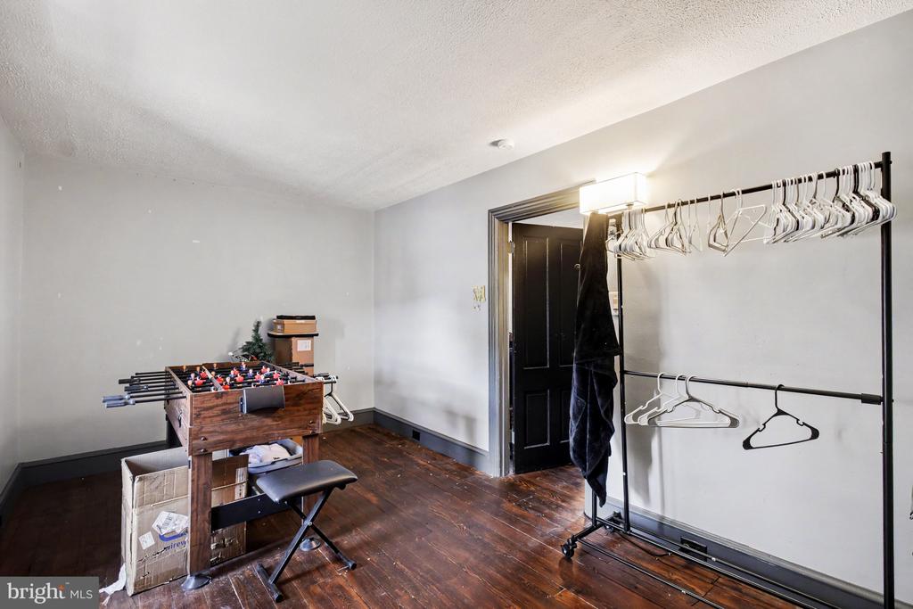 Interior room with dark hardwood floors, a foosball table, and freestanding clothing racks.
