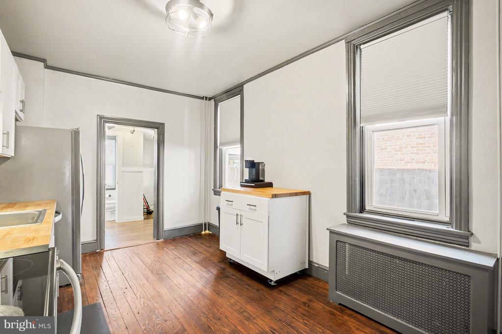 Kitchen with dark-trimmed windows, hardwood floors, and a small white cabinet with a wood top.