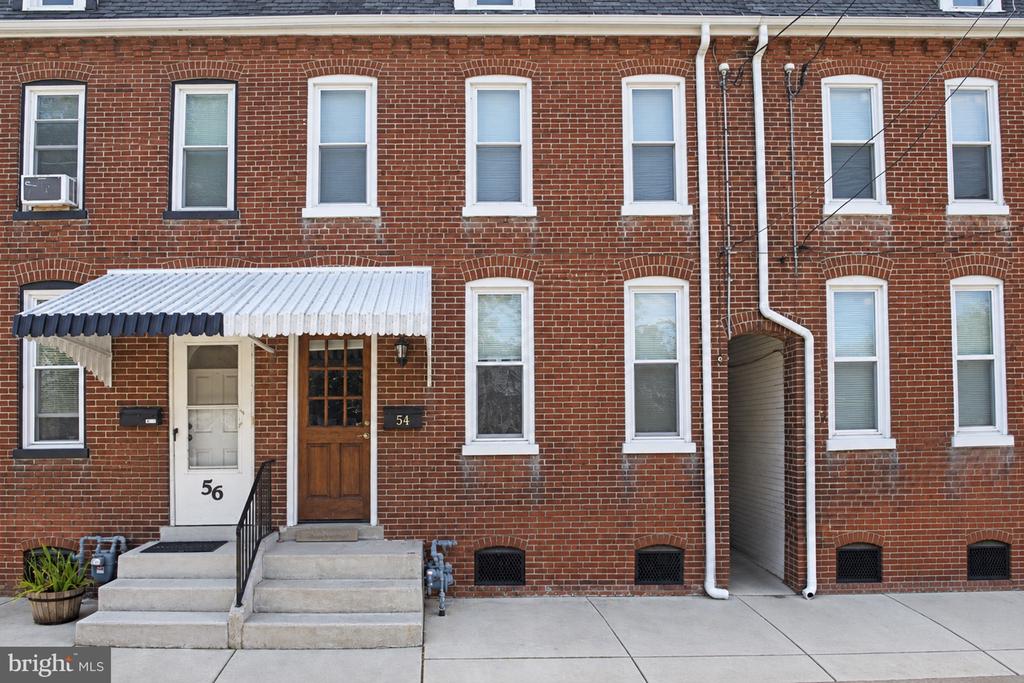 Red-brick rowhouse at 54 S 8th Street, with a wooden entrance door and concrete front steps.
