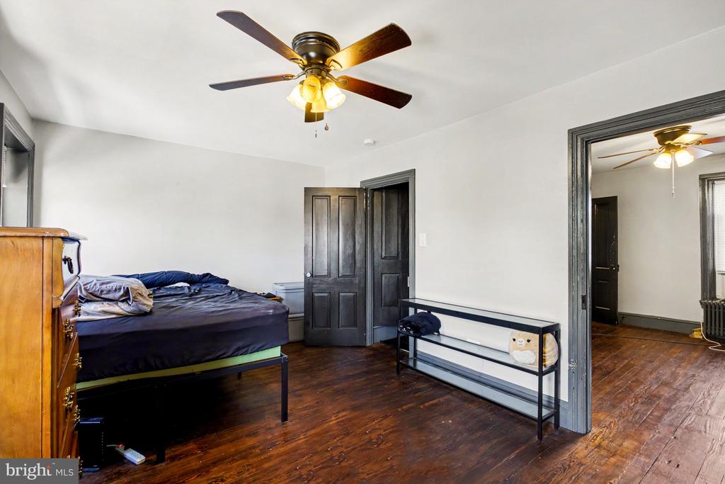 Bedroom with dark hardwood floors, a wooden dresser, and a ceiling fan.