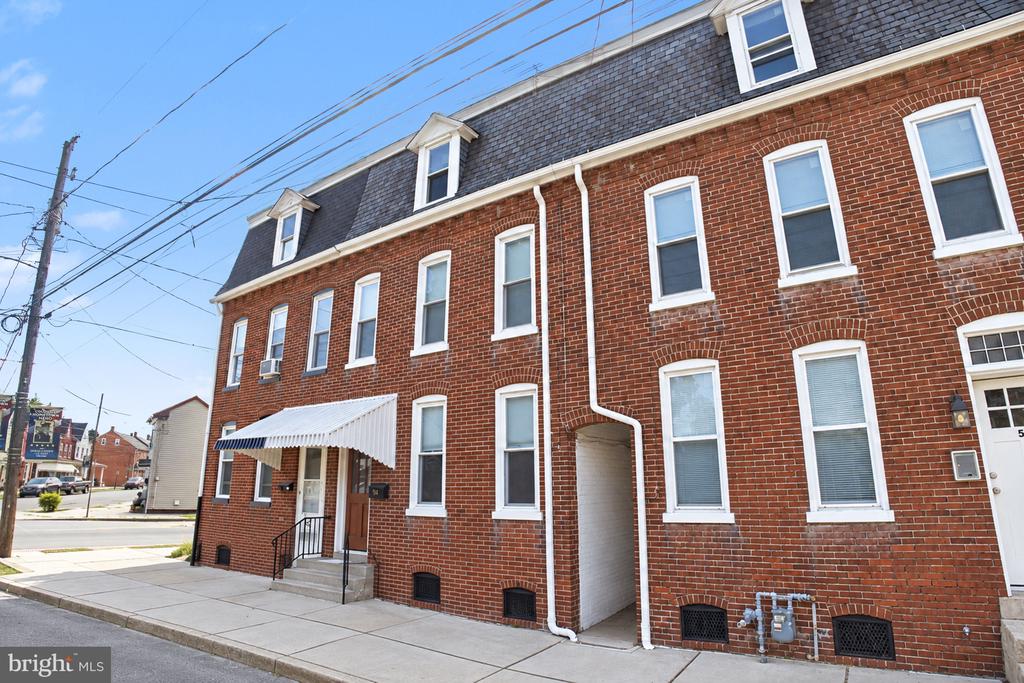Red-brick row building with white-trimmed windows and a striped awning over the entrance.