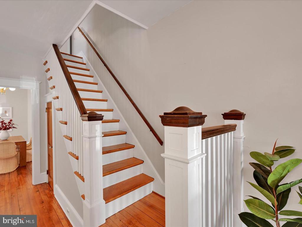 Interior staircase with white balusters, warm wood treads and handrails, and hardwood floors.