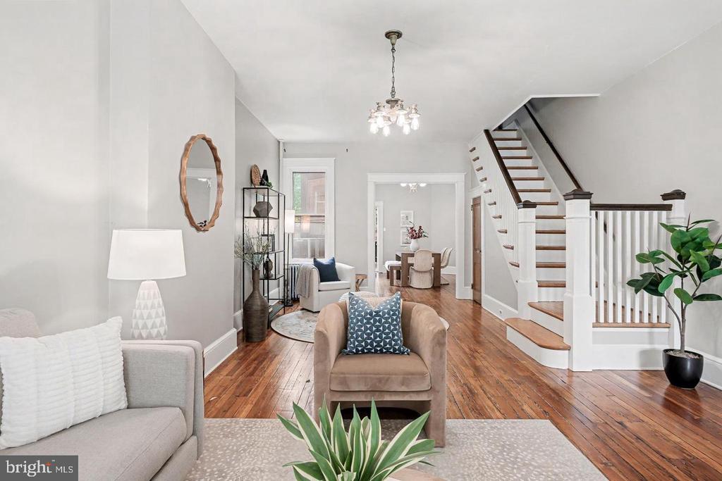 Staged living room with hardwood floors, a staircase, and an adjoining dining area.