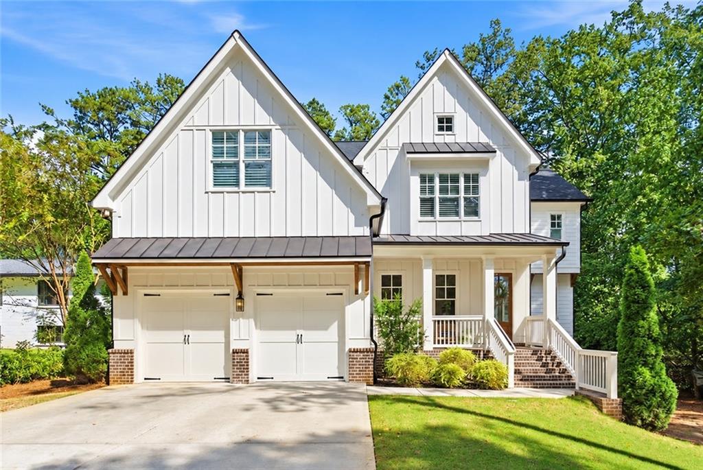 White two-story house with steep gables, a covered porch, and a two-car garage.