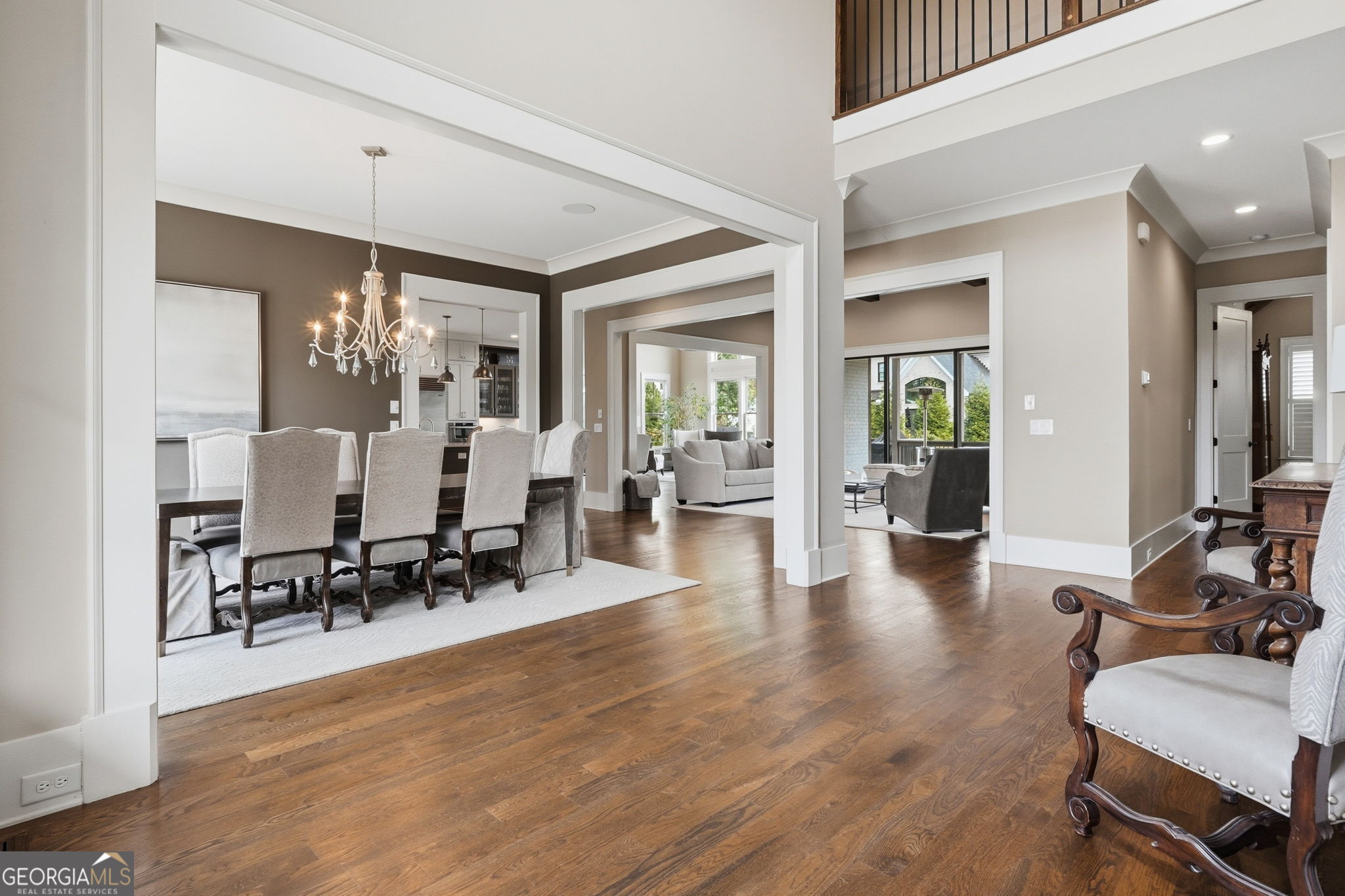 Open dining and living areas with hardwood floors, a chandelier, and views through to the back of the home.