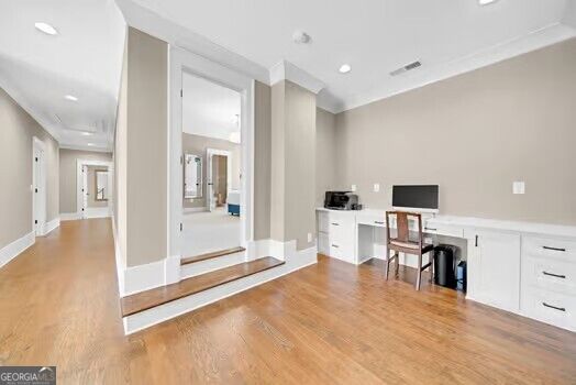 Interior room with built-in white cabinets, a small desk, and steps to an adjoining space.