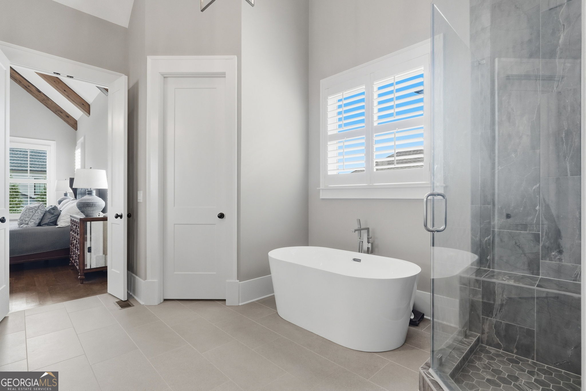 Primary bathroom with a freestanding tub, glass shower, and gray tile.
