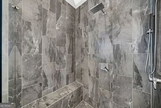 Walk-in shower with gray marble-look tile, a built-in bench, and chrome fixtures.