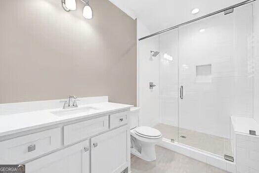 Bathroom with white vanity, toilet, and glass-enclosed walk-in shower.