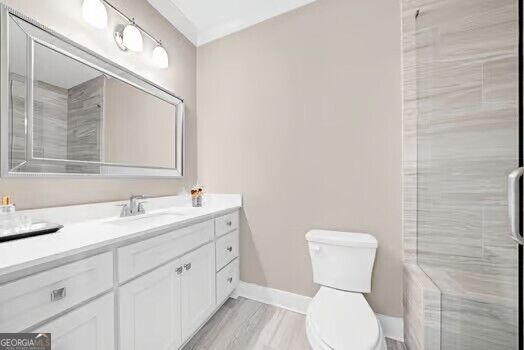 Bathroom with a white vanity, large mirror, toilet, and gray tiled shower.