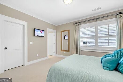 Bedroom with aqua bedding, turquoise pillows, white plantation shutters, and a wall-mounted television.