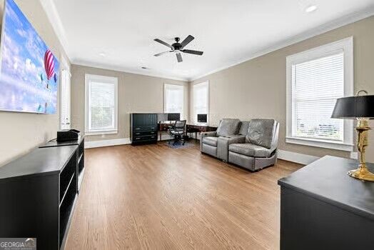 Living room with a gray reclining sofa, light wood floors, and large windows with white blinds.