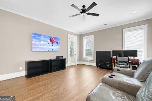 Furnished room with a gray sectional, computer desk, black cabinets, and light wood flooring.