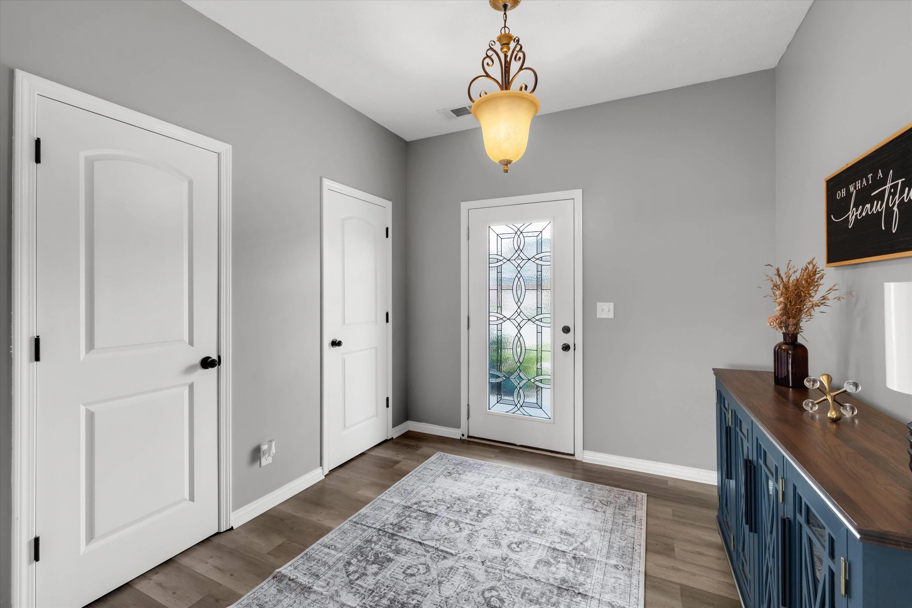 Entryway with a patterned-glass front door, blue console cabinet, and pendant light.