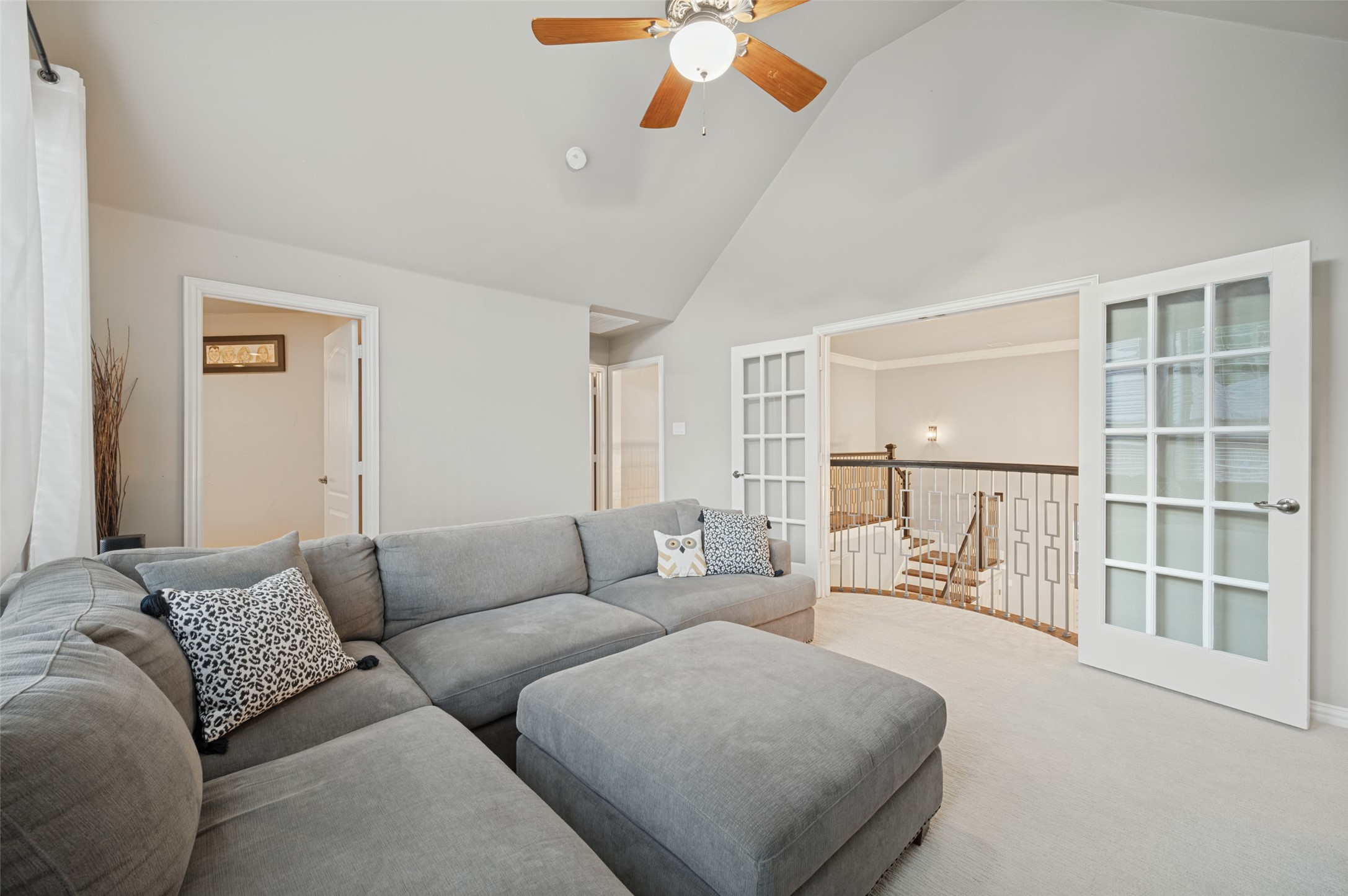 Upstairs living room with a gray sectional and French doors opening onto a staircase landing.