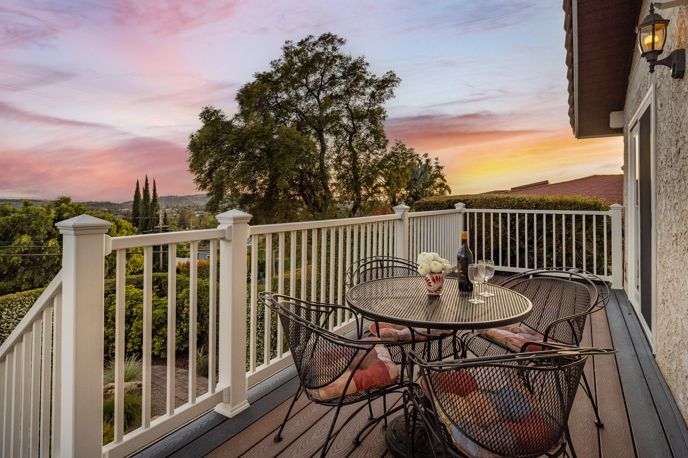 Deck dining area overlooking a tree-lined hillside at sunset.