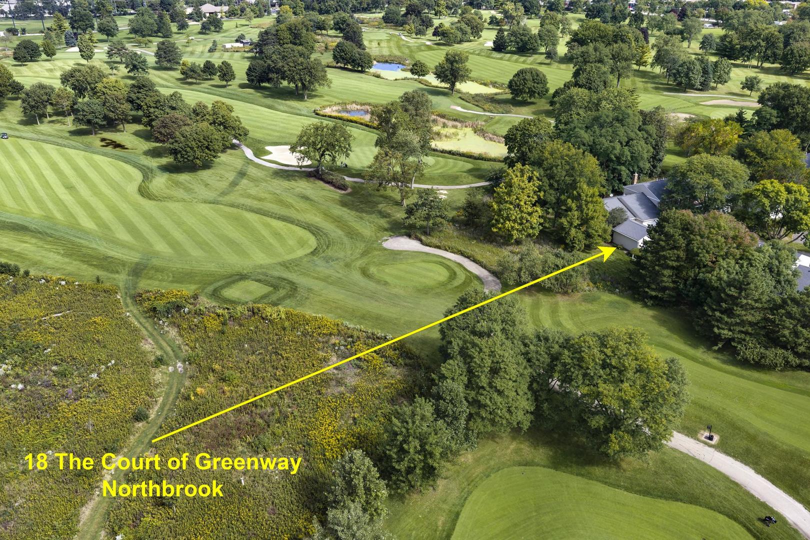 Aerial view of a gray-roofed home beside a golf course, marked by a yellow arrow.