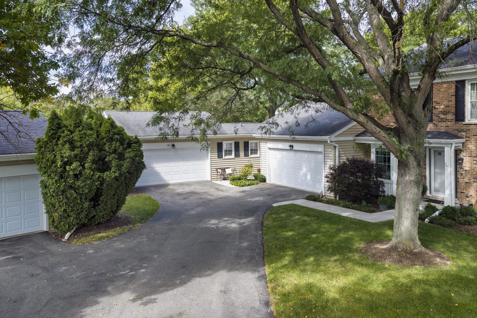 Attached homes with white garage doors beneath mature trees, with house numbers 18 and 19 visible.