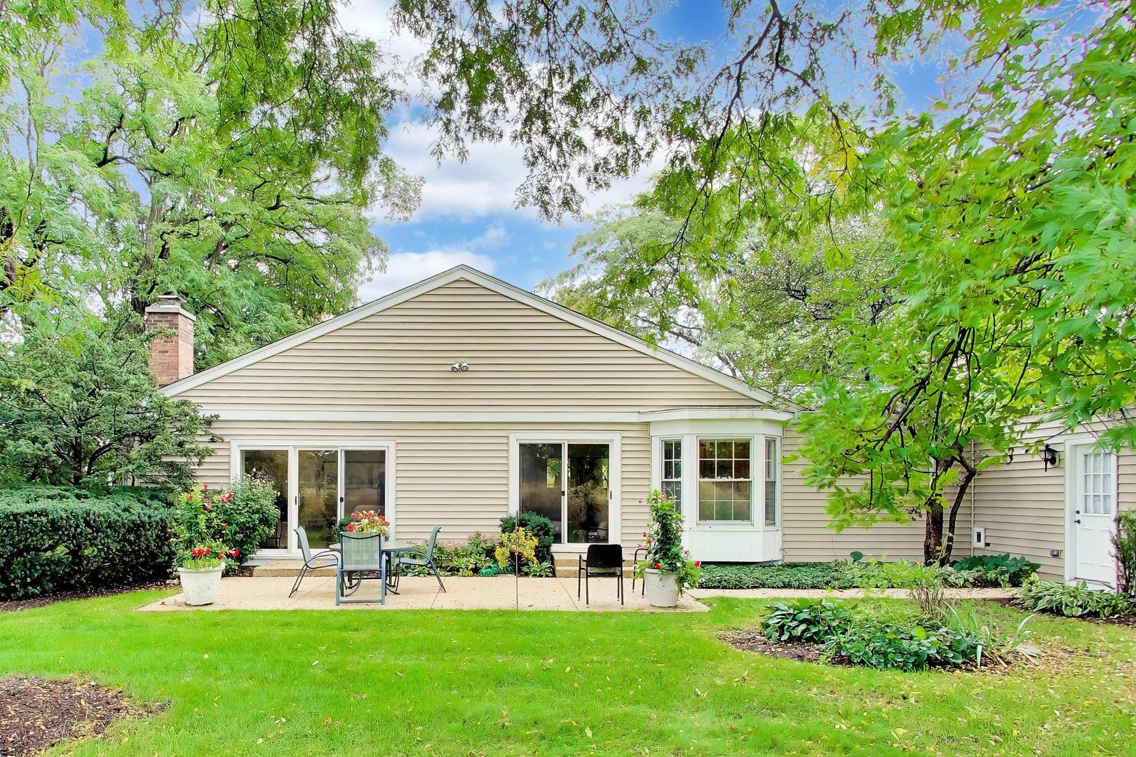 Home’s rear exterior with a furnished patio, bay window, and leafy garden.
