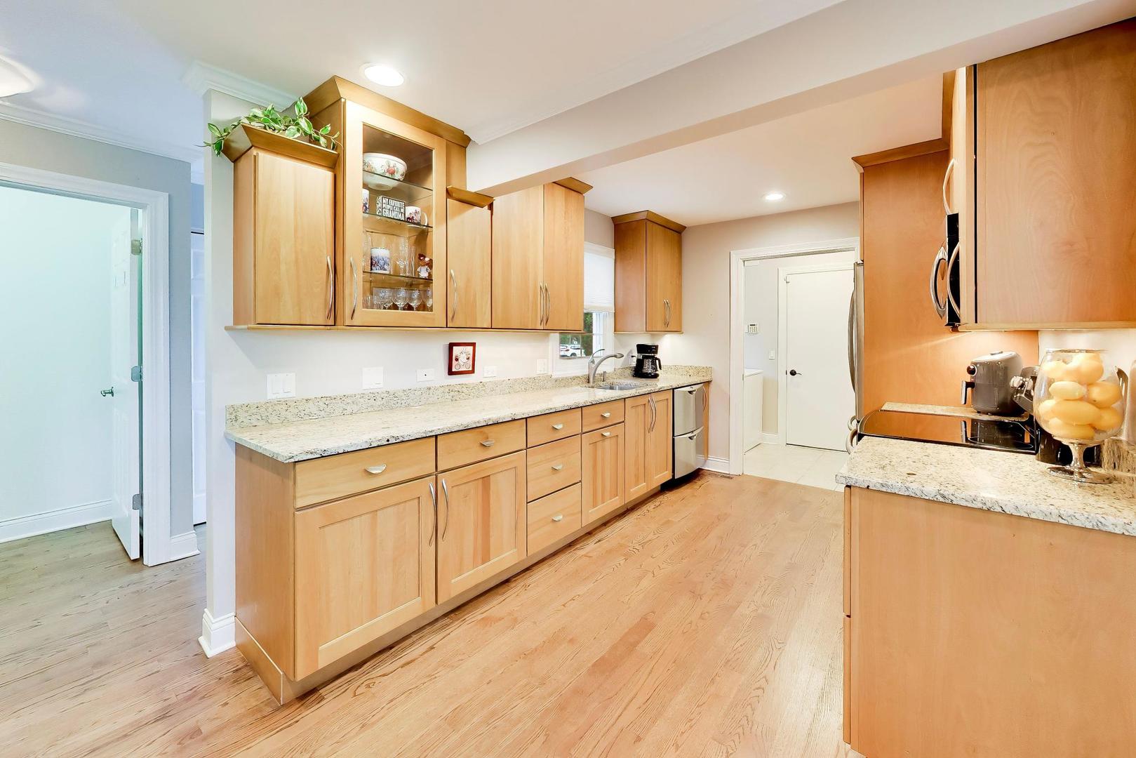 Kitchen with honey-colored wood cabinets, granite countertops, and hardwood floors.