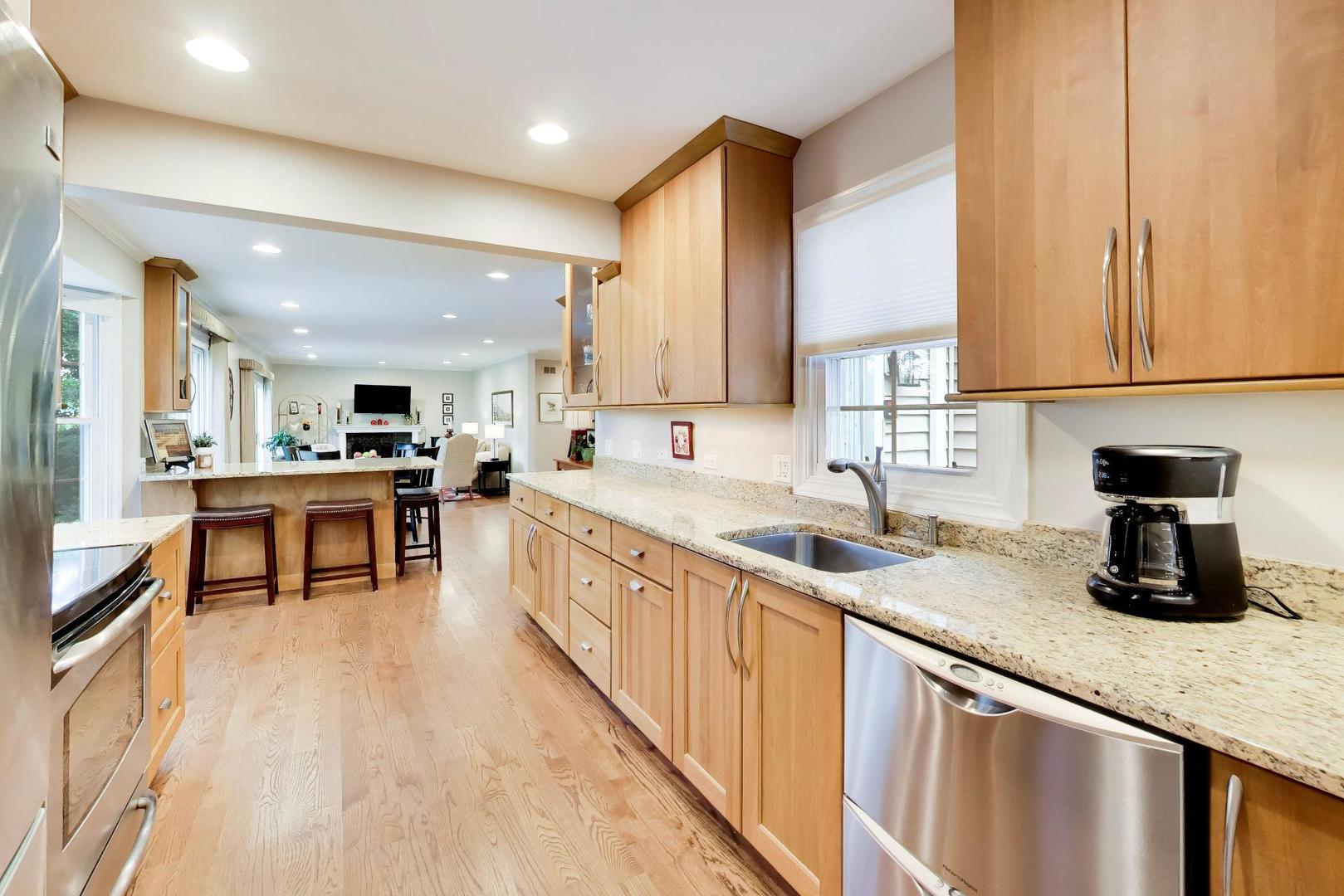 Bright kitchen with light wood cabinets, granite counters, stainless steel appliances, and a breakfast bar.