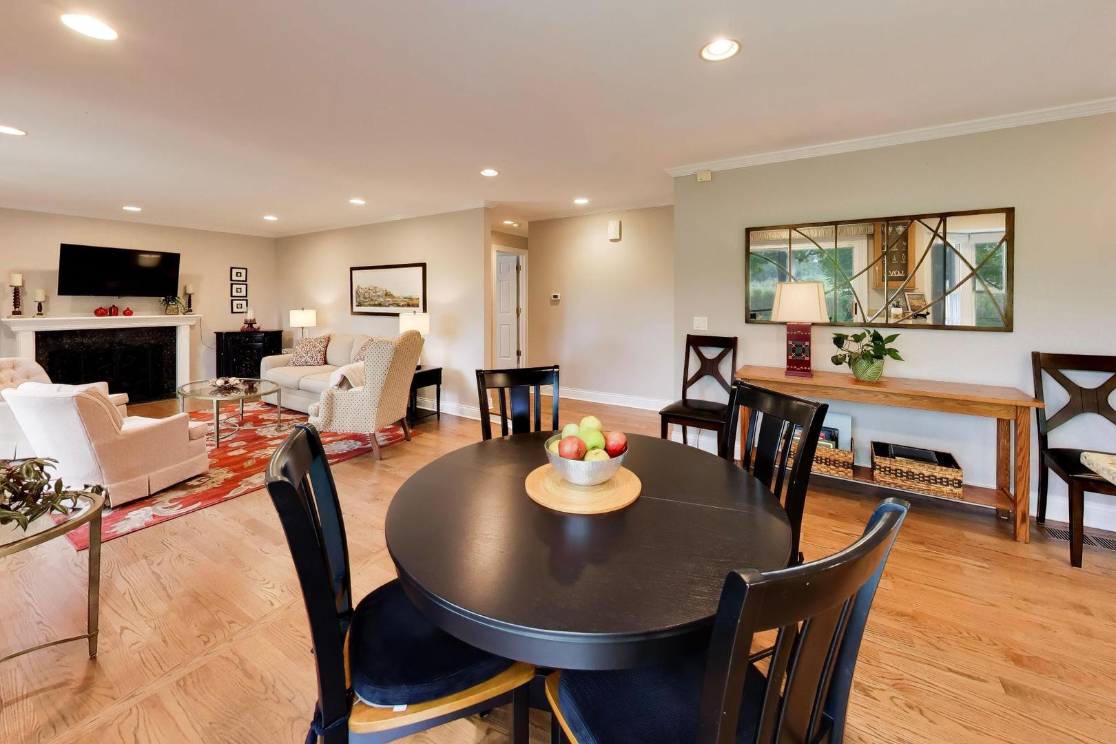 Open-plan living and dining room with hardwood floors, a fireplace, and a round dining table.