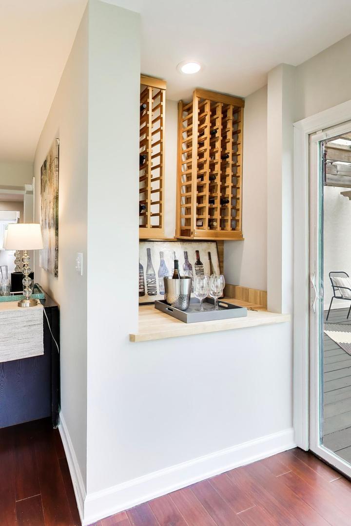Built-in wooden wine racks above a serving counter beside a glass door to the deck.