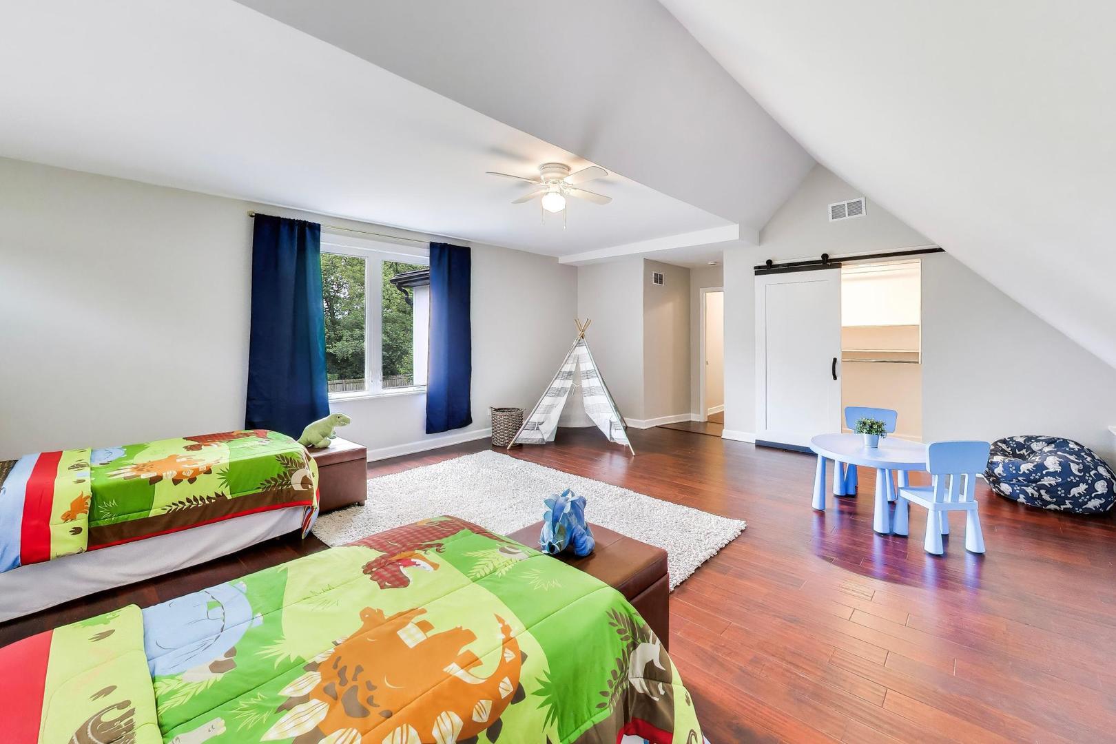 Bedroom with colorful animal-print bedding, a play tent, and a vaulted ceiling.