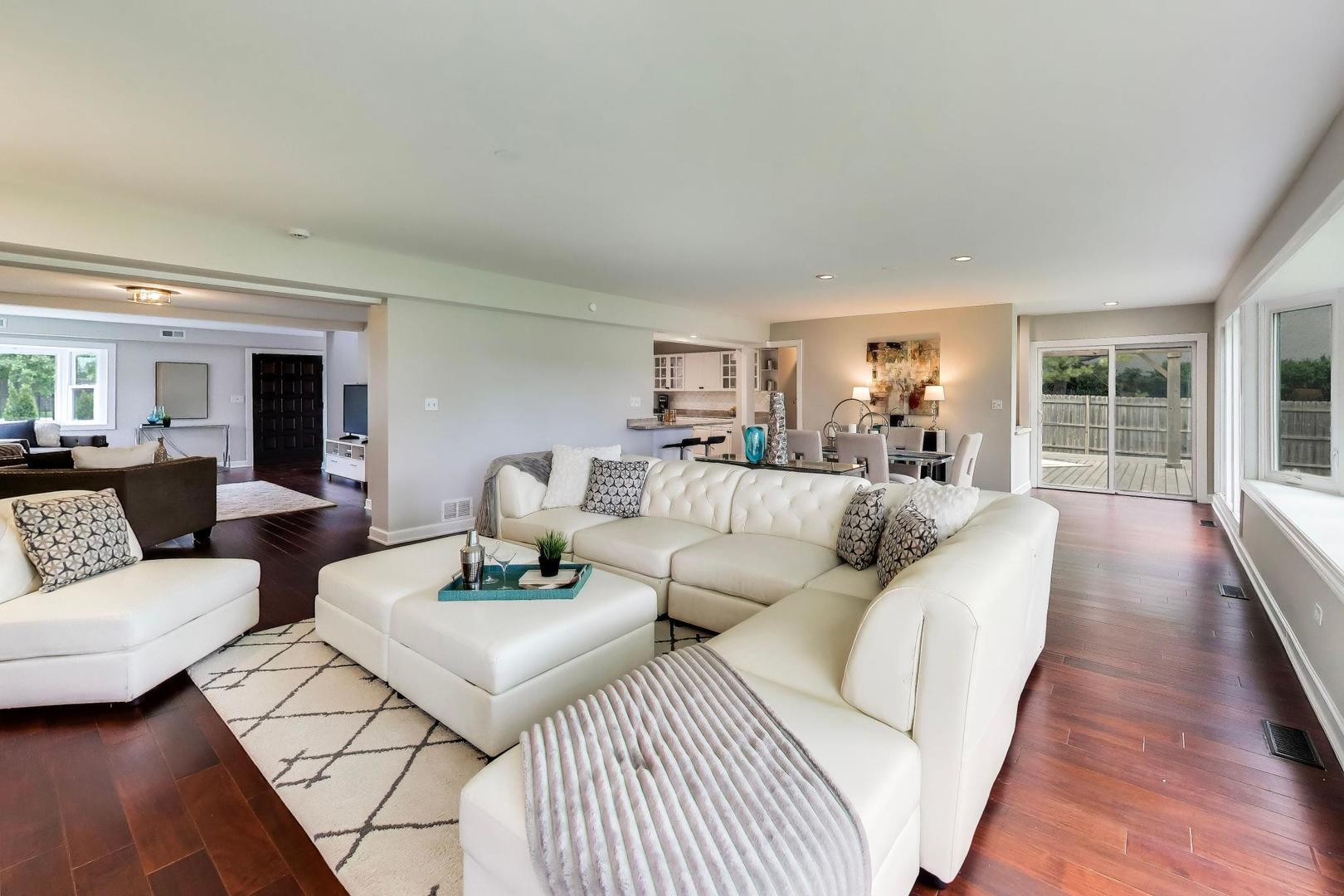 Open-plan living room with a white sectional, dark hardwood floors, and sliding doors to a deck.