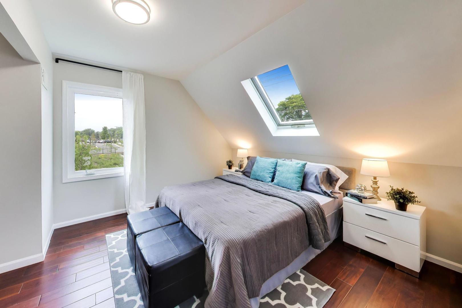 Furnished bedroom with a skylight above the bed and turquoise accent pillows.